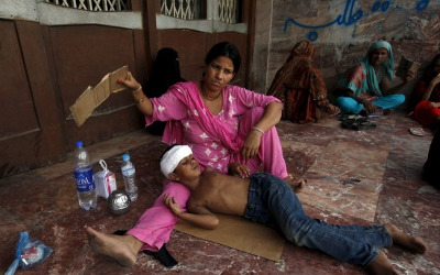 A woman uses a piece of cardboard to fan her son while waiting for a medical