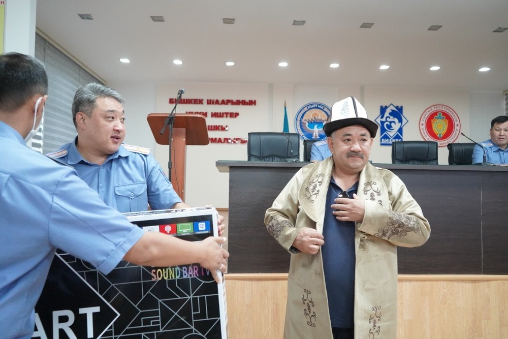 Начальник ГУВД Бишкека Азамат Ногойбаев вручает памятные подарки бывшему начальнику Первомайского РУВД Акылбеку Казакееву.