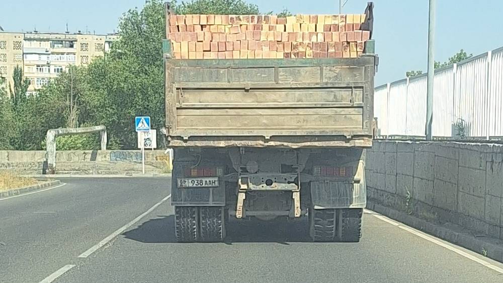 Груженный самосвал едет по городу в +37. Фото
