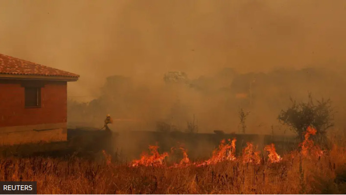 Пожарный борется с лесным пожаром возле дома в Конгосте, Испания