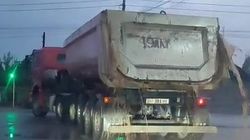 Из прицепа грузовика, выезжающего с карьере, на дорогу течет грязь и ил. Видео