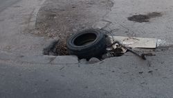 На дороге яма закрыта резиновой покрышкой и мусором