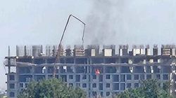 Из строящегося здания в районе шлагбаума идет дым
