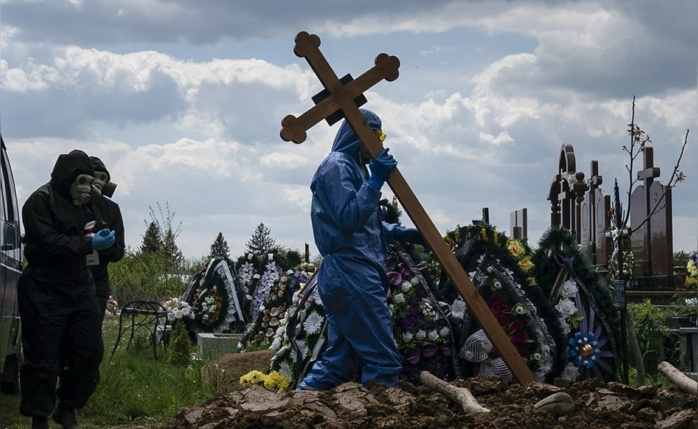 Работники кладбища, одетые в защитное костюмы, готовятся похоронить тело умершего от коронавируса, Украина