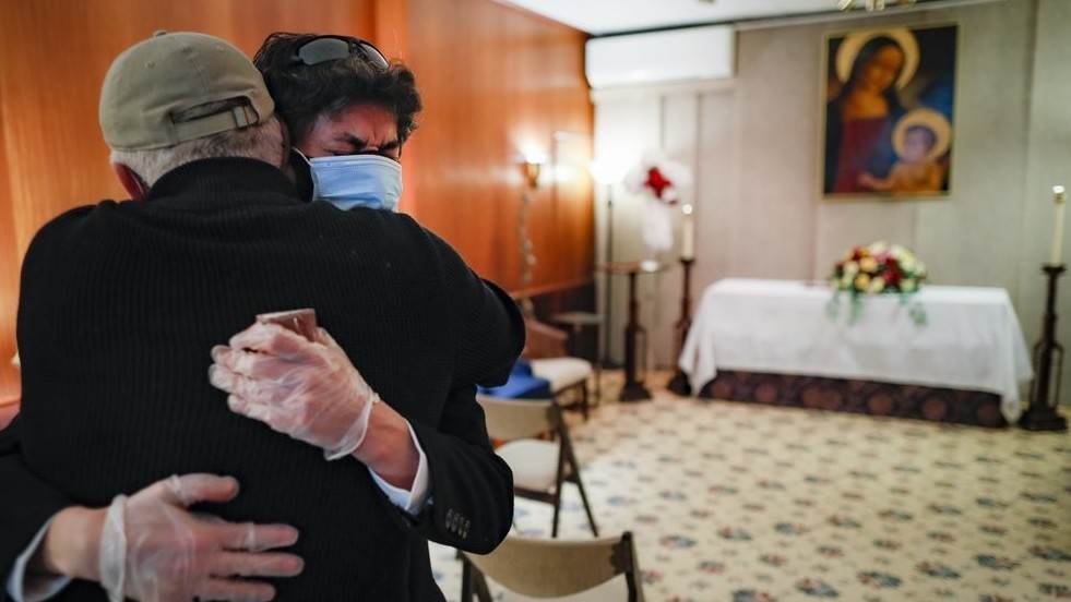 Леонардо Кабанья плачет в объятиях своего друга Рафаэля Беневидеса рядом с гробом своего отца, который умер от коронавируса, Ньй-Йорк, США