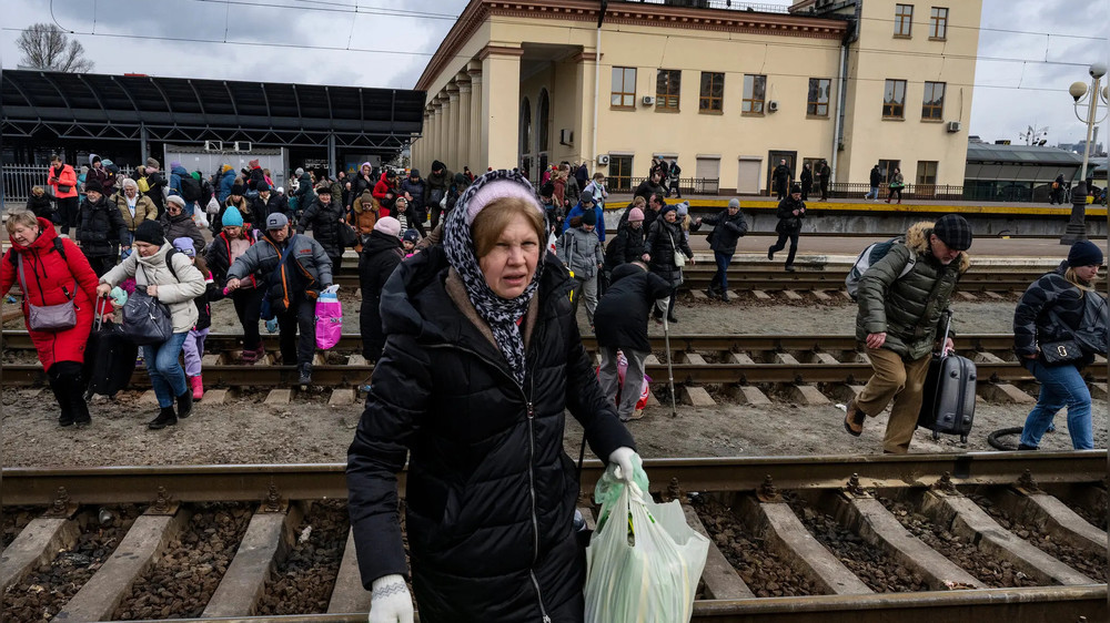 Украинские семьи бегут через рельсы к эвакуационному поезду