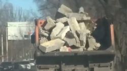 КамАЗ с открытым бортом везет бордюры. Видео