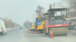 Сотрудник ГУОБДД стоит, спрятавшись за техникой для укладки асфальта. Видео