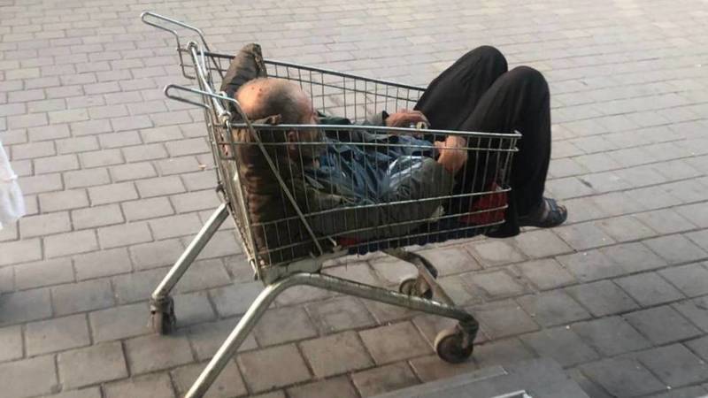 Бездомный спит в продуктовой тележке возле «Народного». Фото
