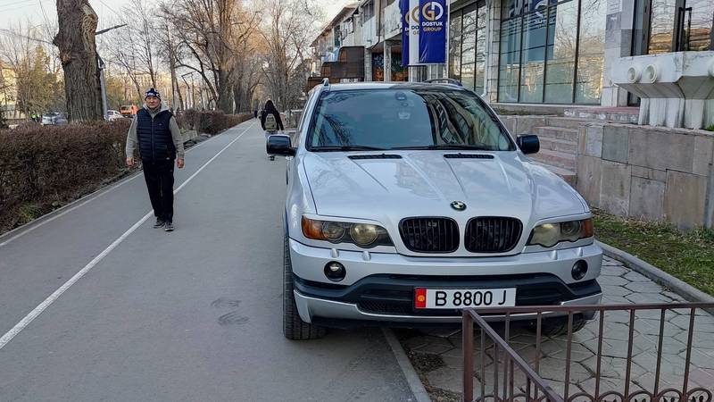 BMW X5 припаркован на тротуаре. Фото
